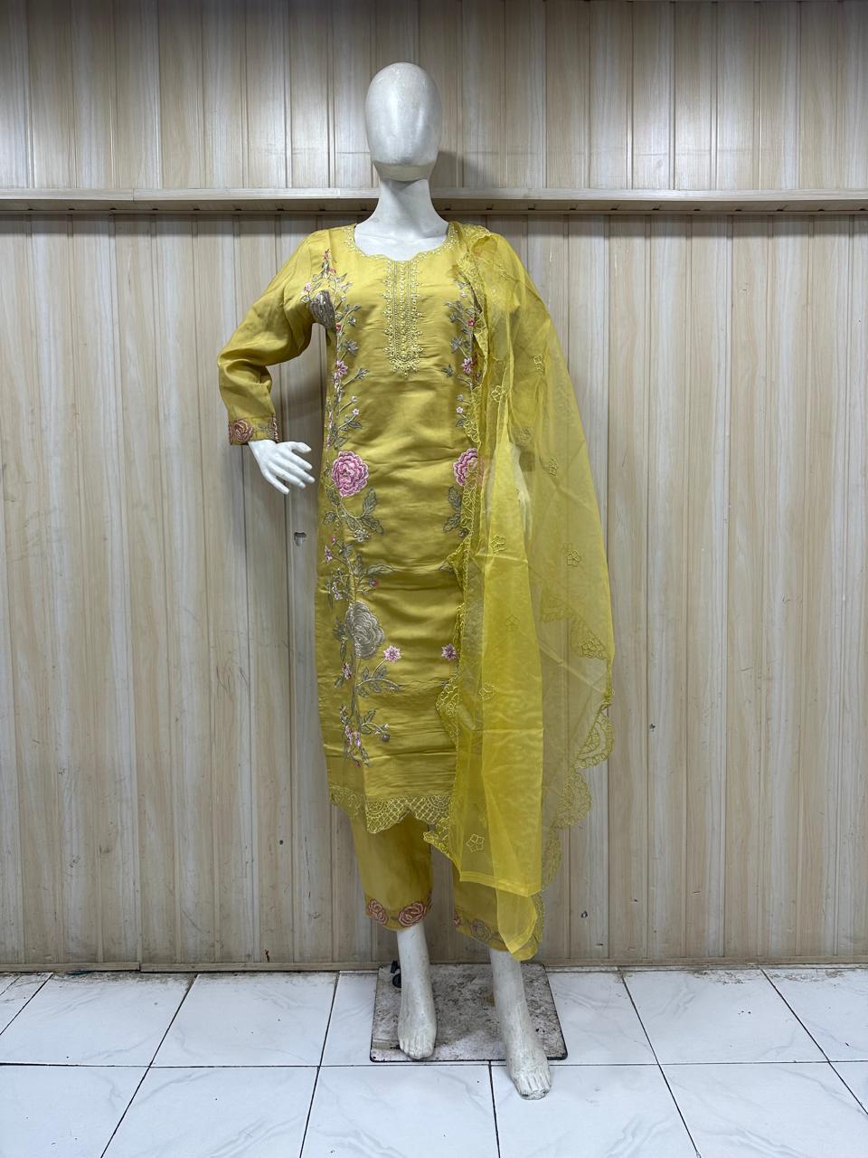 mannequin yellow embroidered traditional outfit with floral dupatta against a striped wall