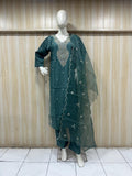 mannequin gereen embroidered traditional outfit with silverl dupatta against a wooden panel bacgraound