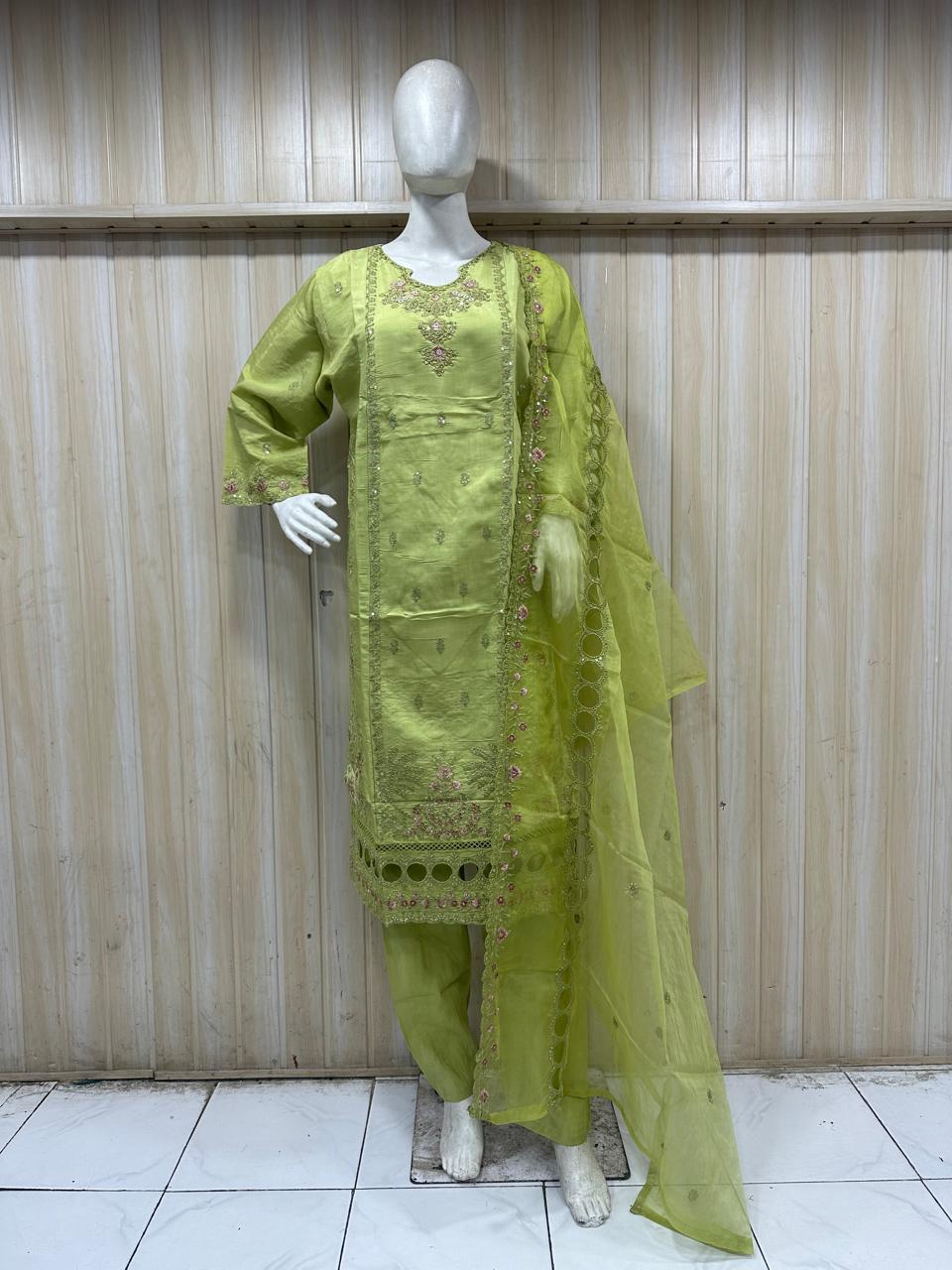 mannequin gereen embroidered traditional outfit with s dupatta against a wooden panel bacgraound