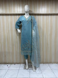 teal embroidered outfit  with dupatta  on a mannequin against a wooden panel background