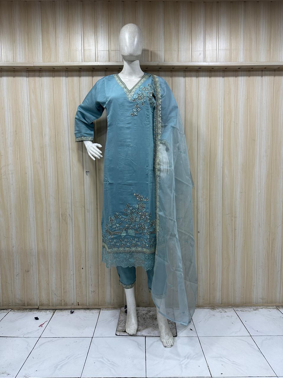 teal embroidered outfit  with dupatta  on a mannequin against a wooden panel background