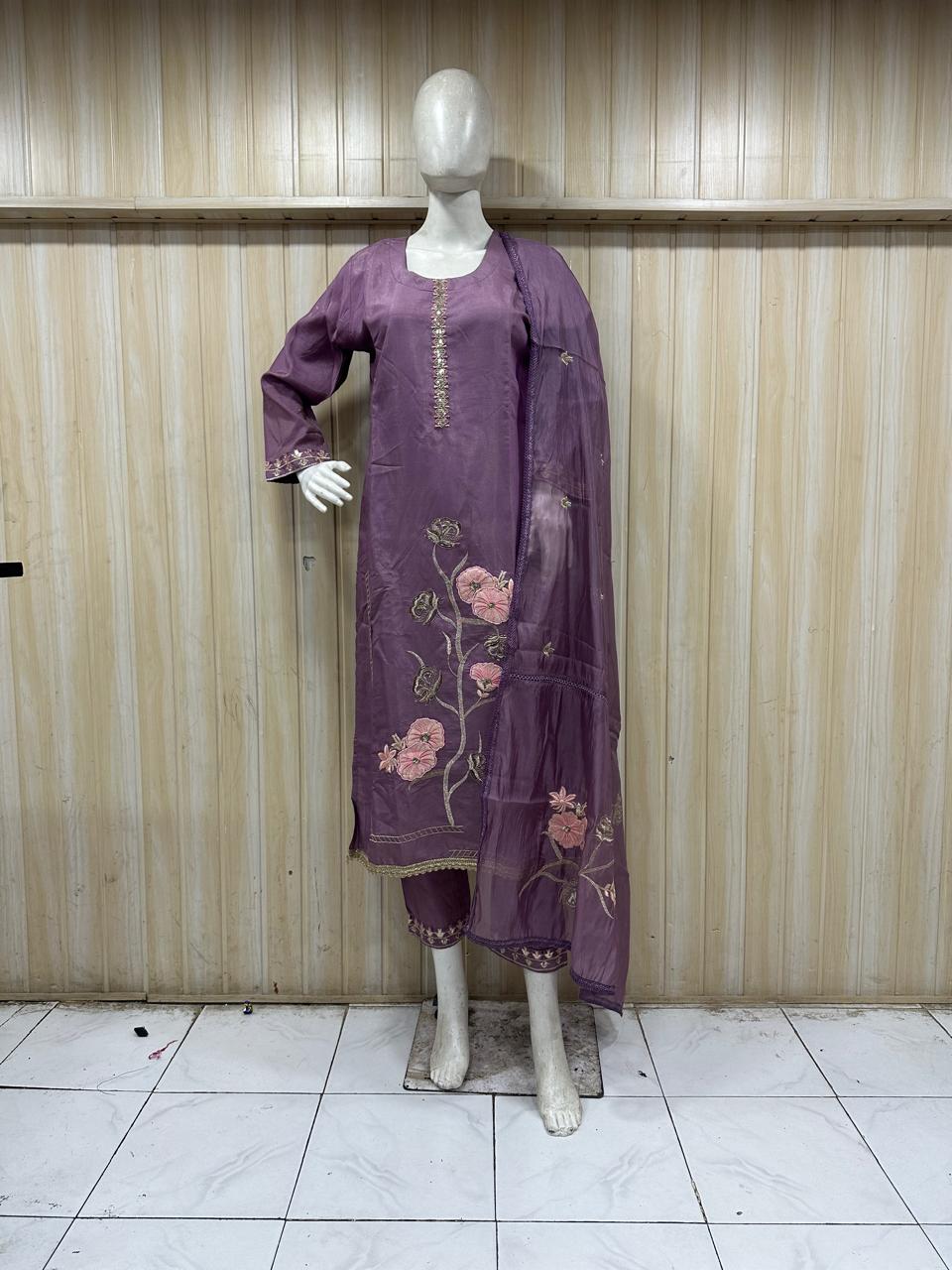 purple embroidered outfit on a mannequin against a striped wall