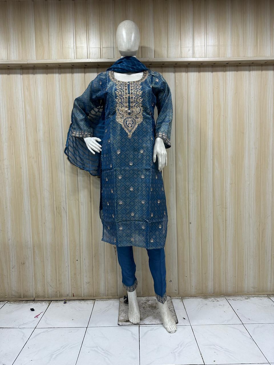 mannequin waering a blue embroidered outfit against a striped wall