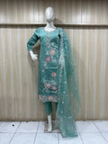 mannequin waering a teal embroidered outfit with a sheer dupatta against a wooden panel
