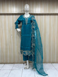 teal drees with lace details on a mannequin against a wooden panel backgroun