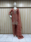 mannequin waering a rust - colored treditional outfith with intricate embroidered against a striped wall