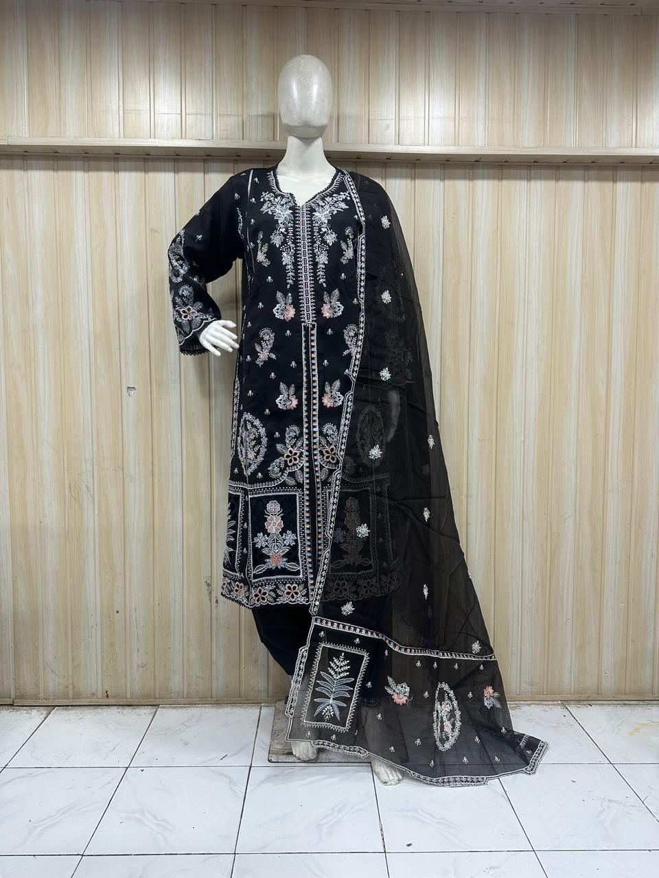 black embroidered treditional outfit with a mannequin against a wooden paneled wall