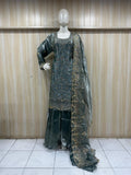 mannequin weaering a traditional adark  green embroidered outfit a against a wooden panel backgrauond