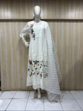 white embroidered dress on a traditional mannequin against a wooden panel back ground
