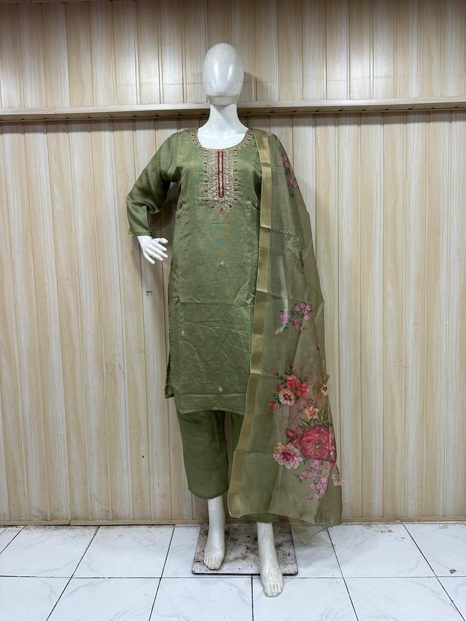 green traditional outfit with embroiered detials on a mannequin against a striped wall