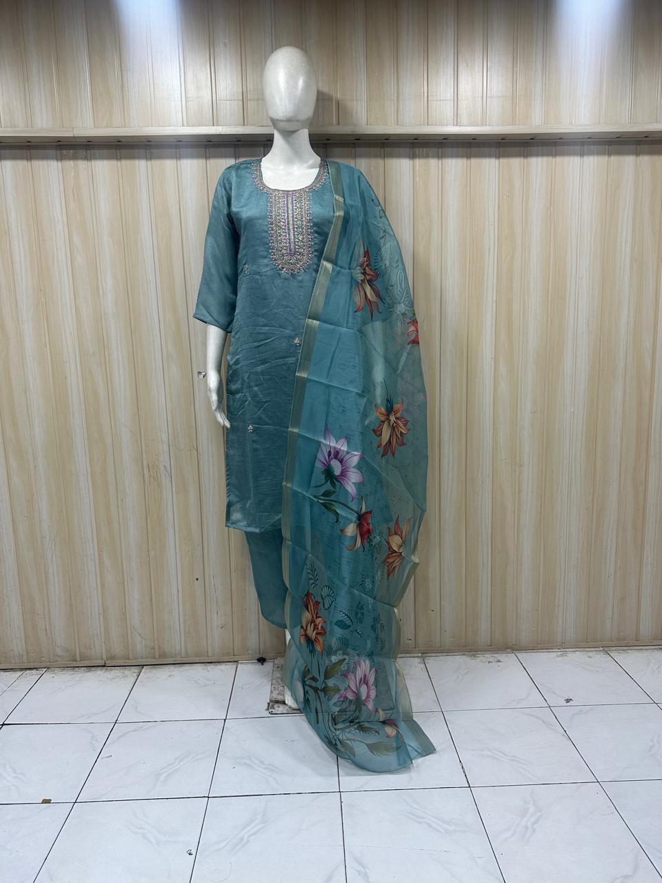 teal embroiered traditional on a annequin against a striped wall