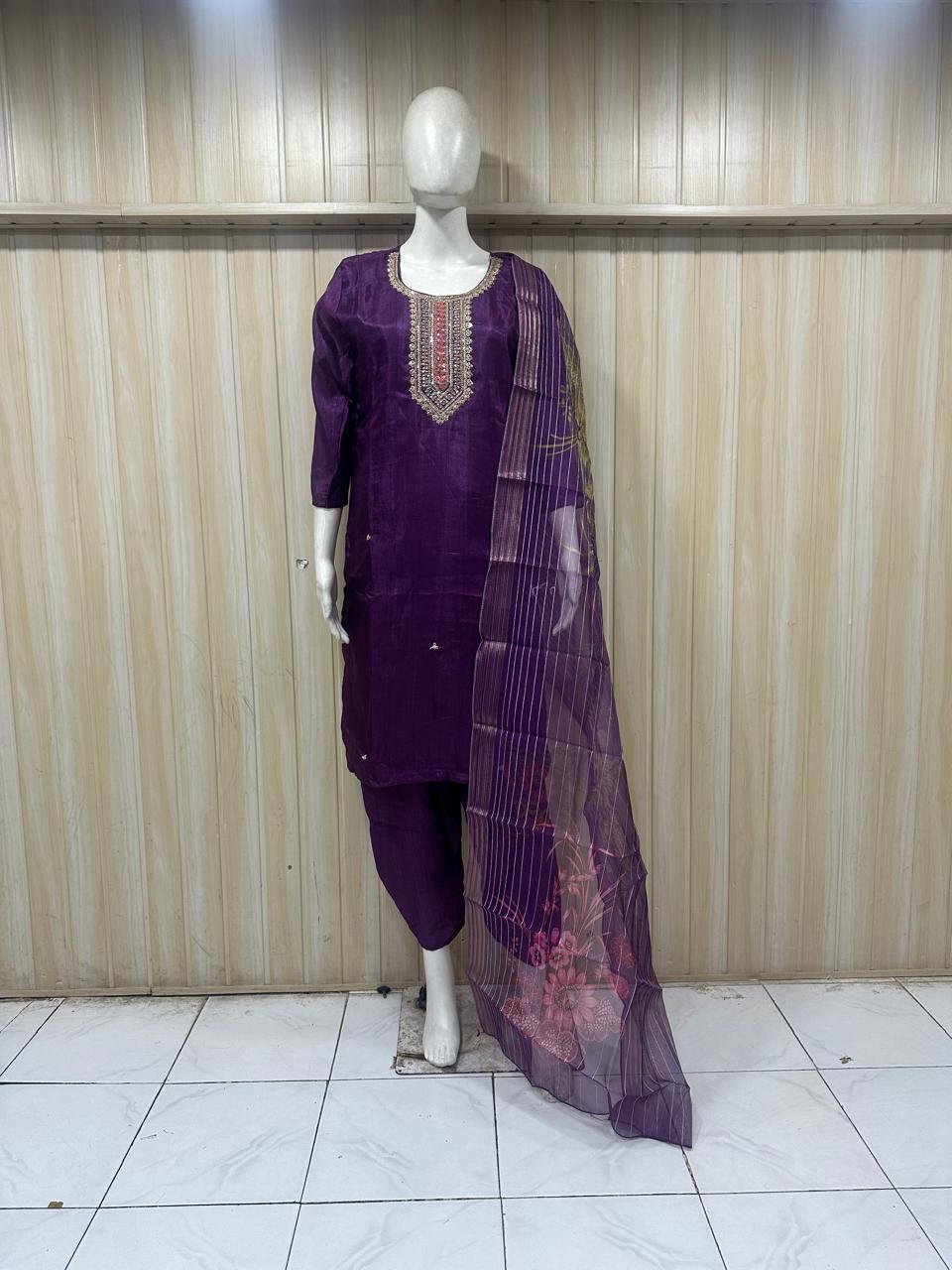 a purpal traditional outfit with dupatta on a mannequin a  against a striped wall
