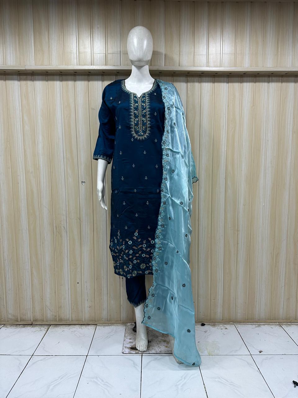 mannequin wearing navy blue embroiderd traditional dress outfit with a light blue dupatta against a striped wall