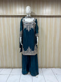 mannequin wearing teal embroidered traditional outfit with a patterns against a striped wall