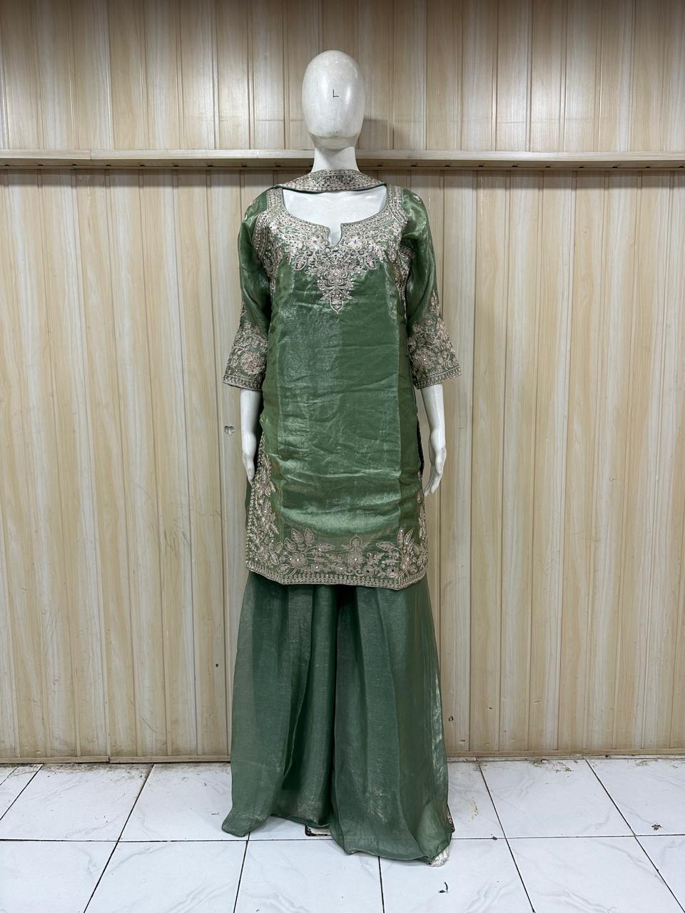 mannequin wearing green embroidered traditional outfit with a patterns against a striped wall