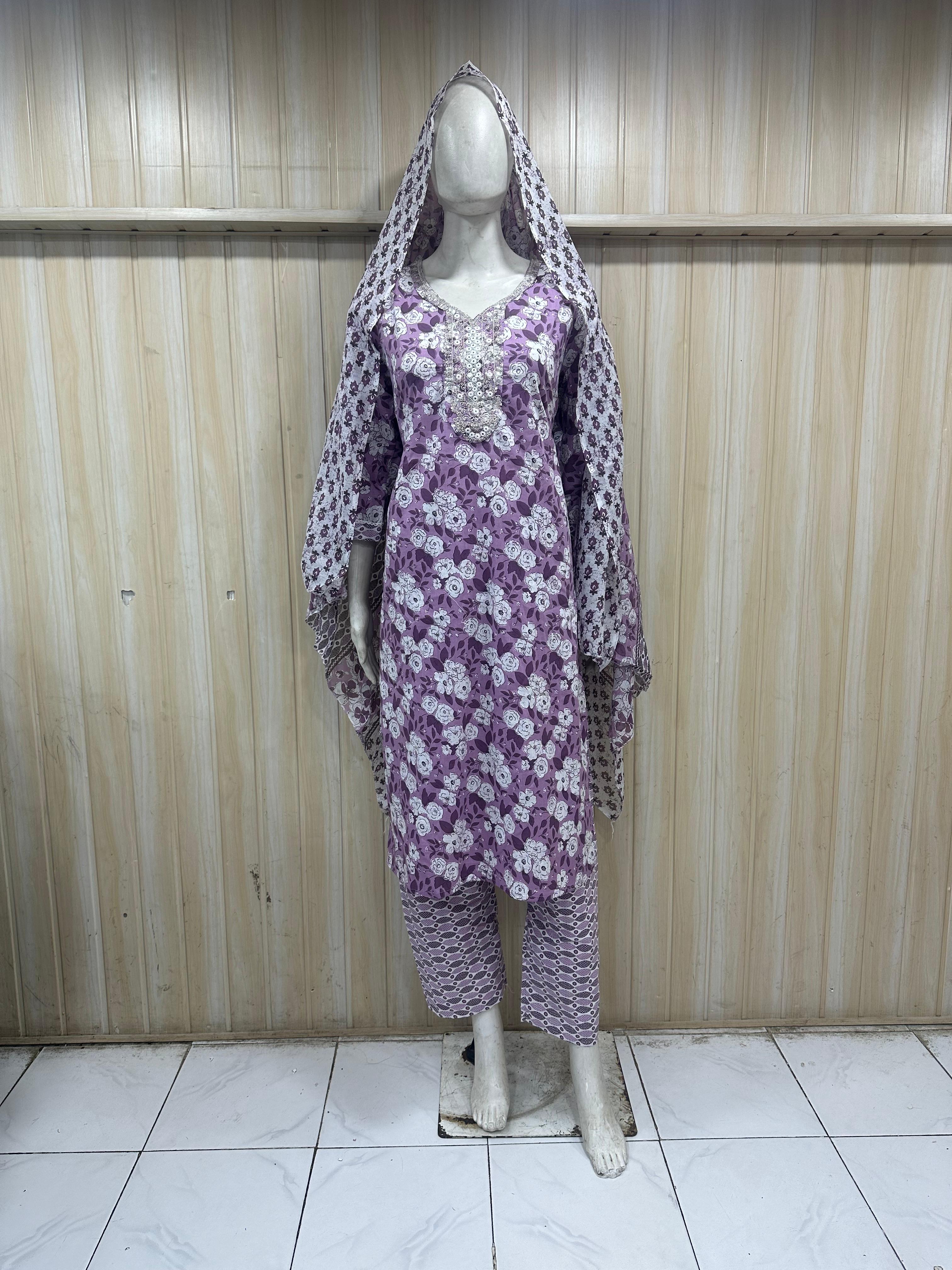 mannequin wearing a purpal patterned traditional outfit with a matching shawl headscraf against a striped wall  ChatGPT3:28 PM
