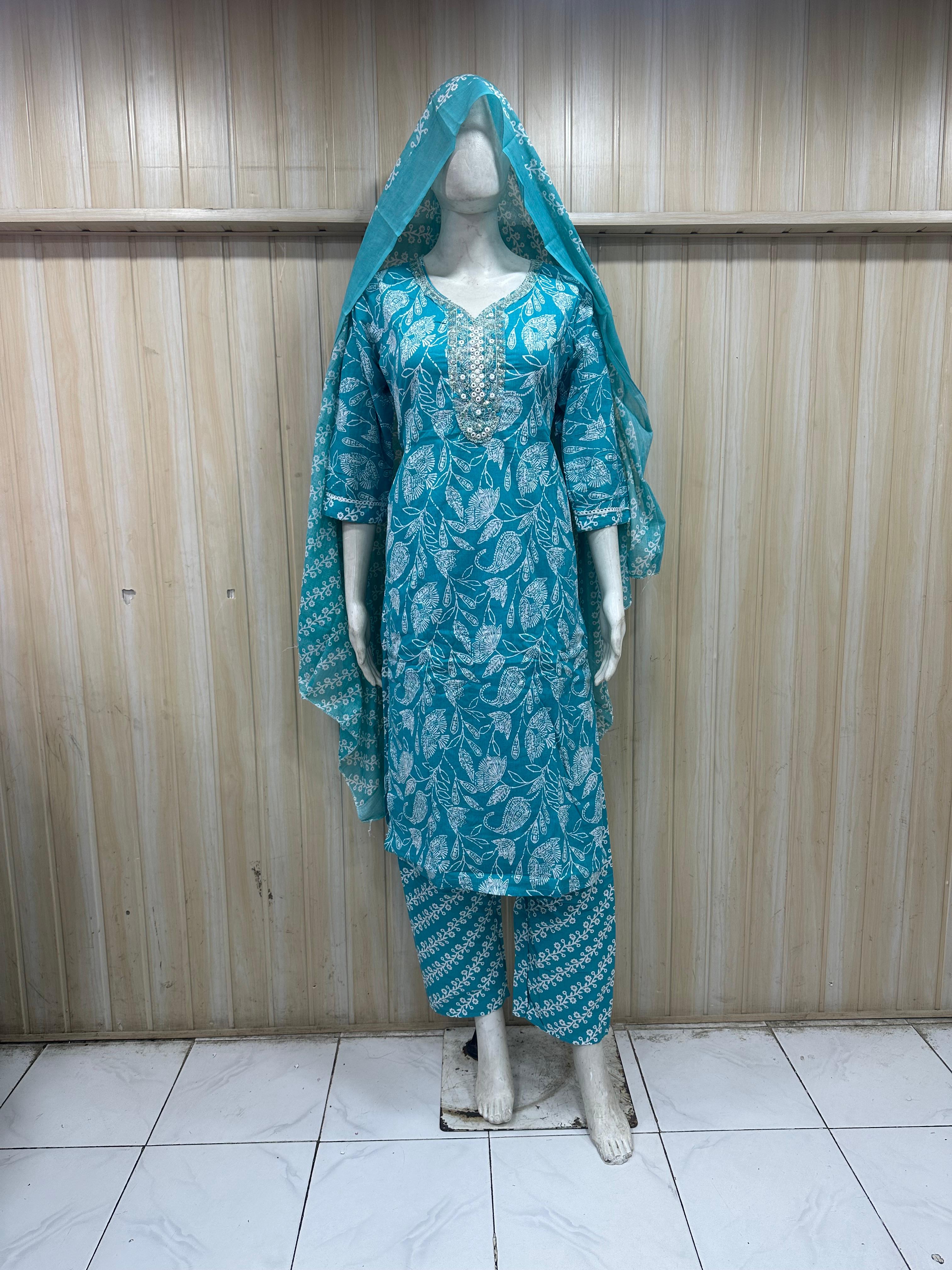 mannequin wearing a purpal patterned traditional outfit with a matching shawl headscraf against a striped wall