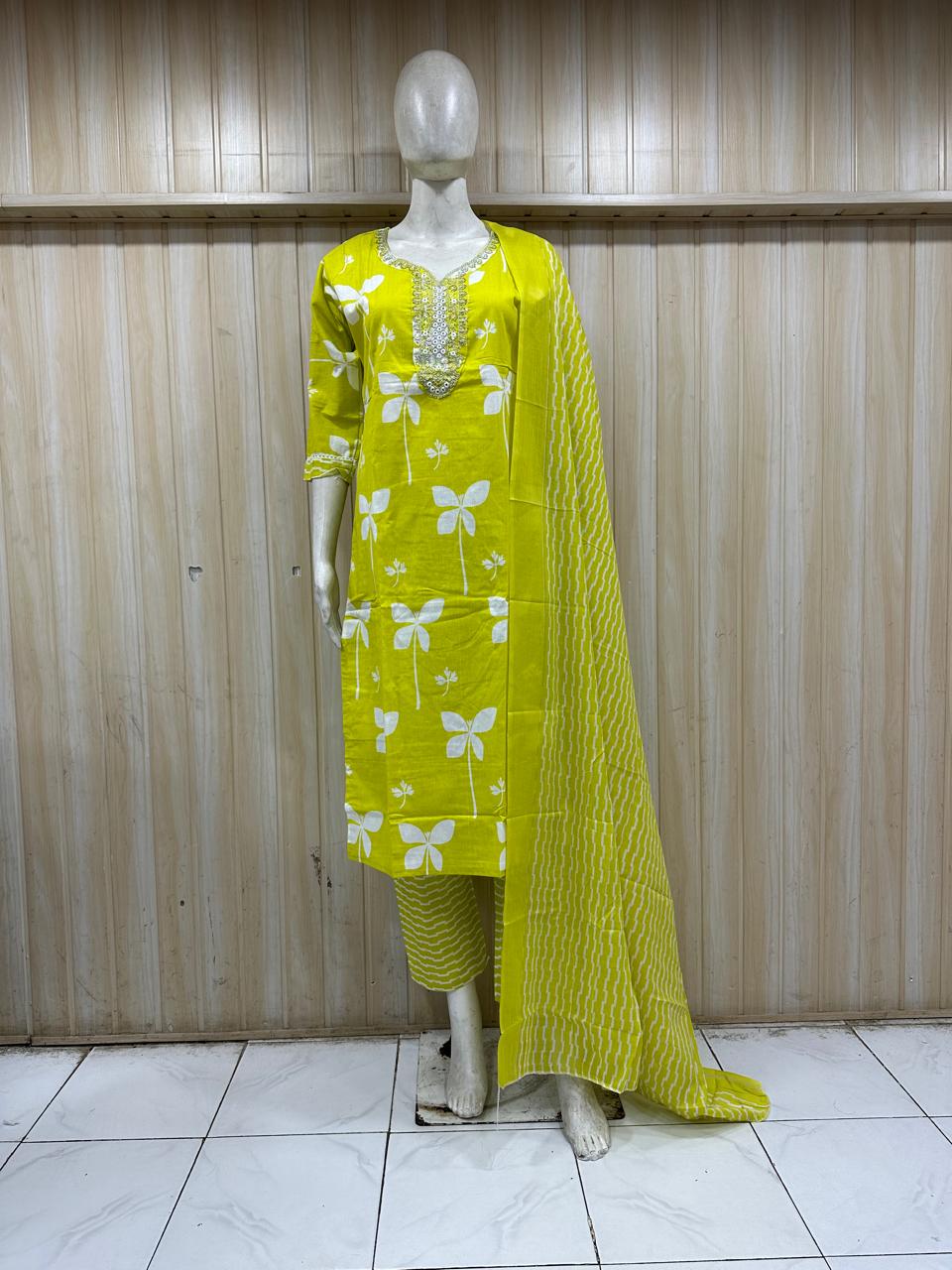 mannequin wearing a light green patterned traditional outfit with a matching dupatta shawl headscraf against a striped wall