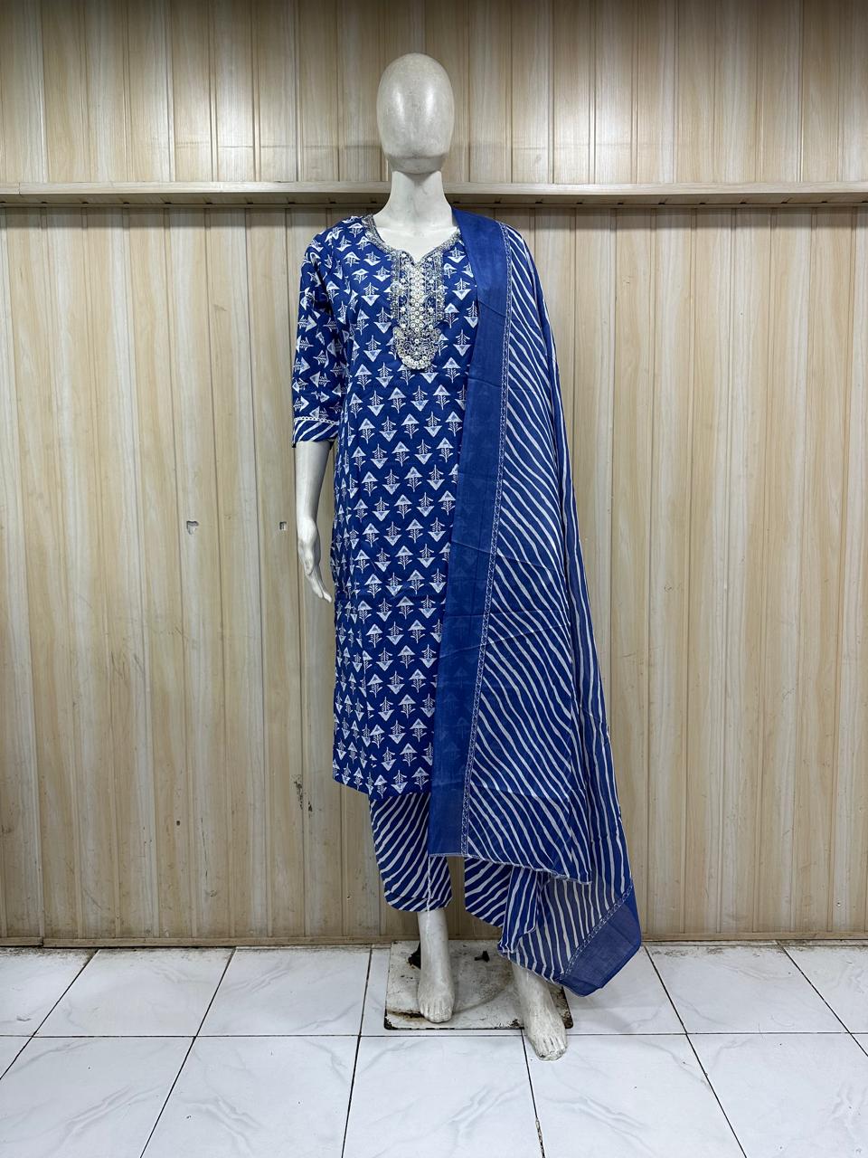 mannequin wearing a blue and white patterned traditional outfit with a matching dupatta shawl headscraf against a striped wall