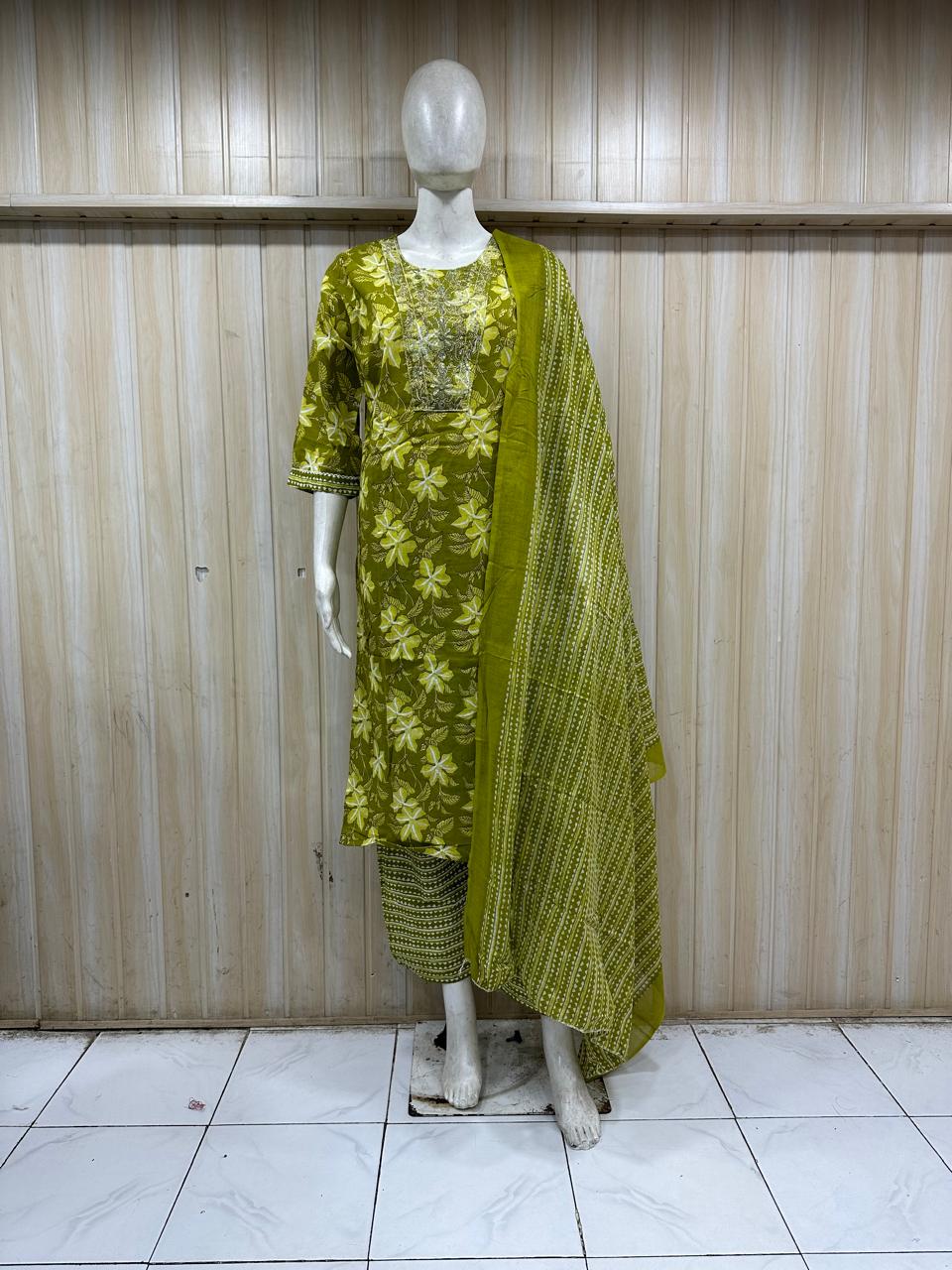 mannequin wearing a green floral outfit with a matching dupatta shawl headscraf against a striped wall