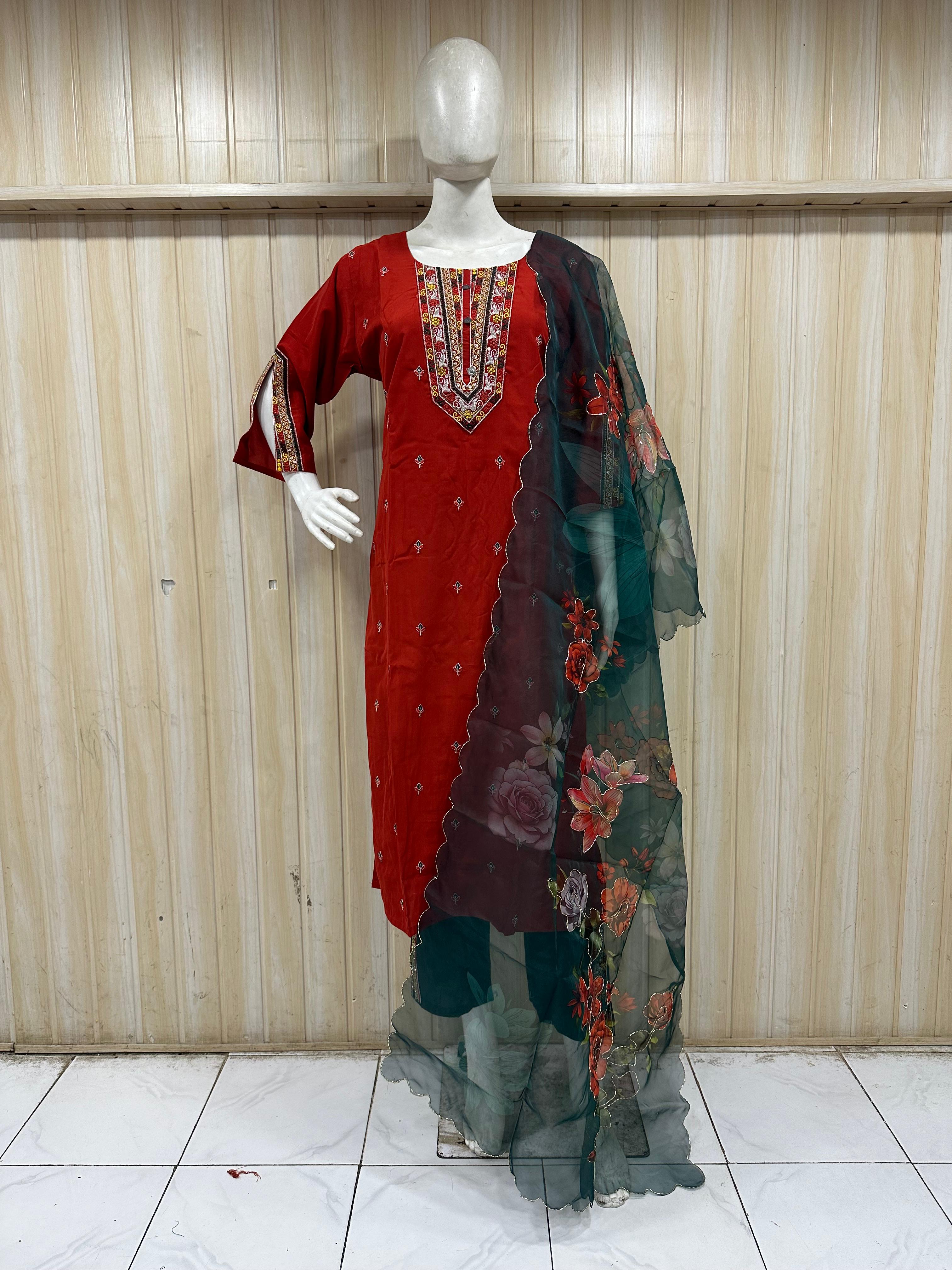 mannequin wearing a red embroidered floral outfit with a dupatta against a wooden panel backgruond