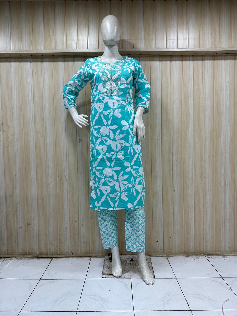 mannequin wearing a teal outfit with dress Floral Traditional against a wooden panel background
