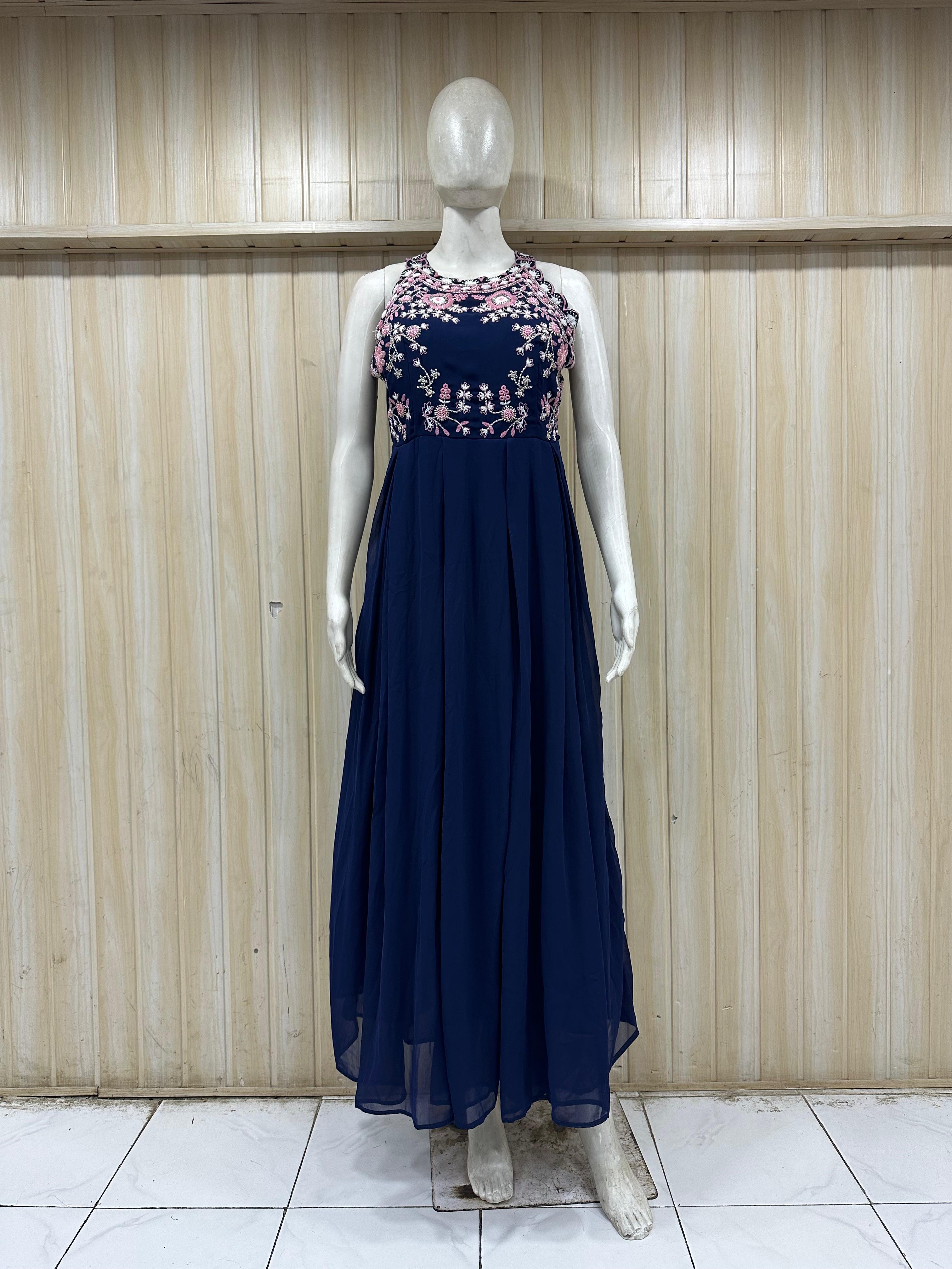 Navy blue dress with floral embellishments on a mannequin against a wooden panel background