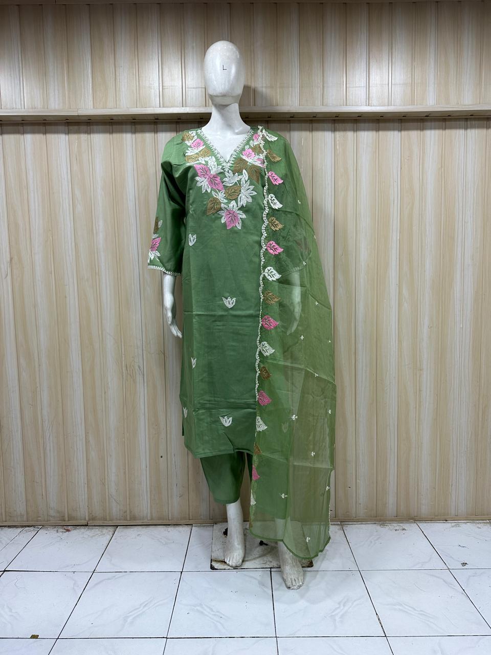 Purple traditional green outfit with pink and white embroidery on a mannequin against a striped