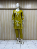 Green outfit with white floral embroidery on a mannequin against a striped