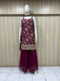 Mannequin wearing a maroon floral embroidered top and green pants against a striped