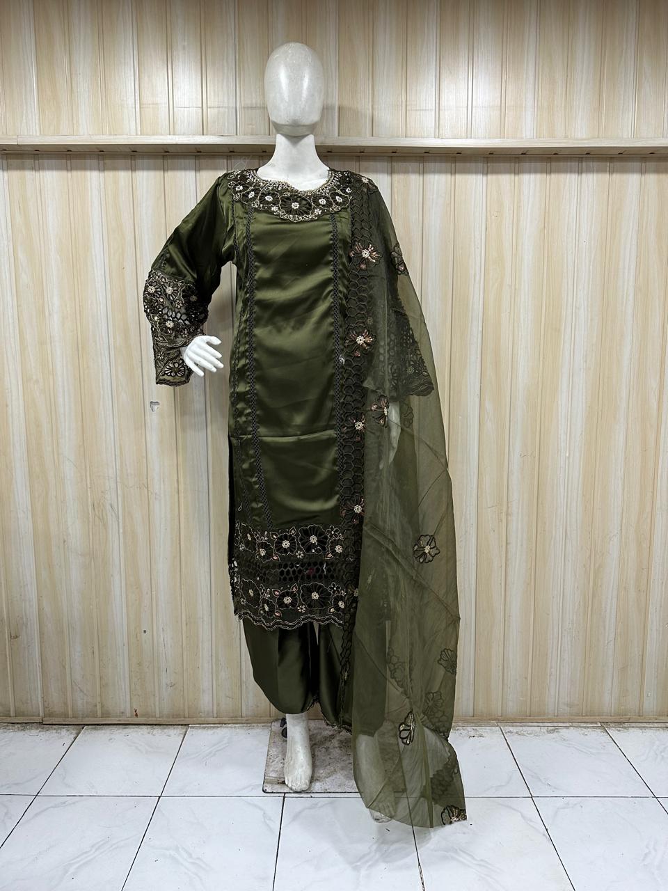Green embroidered traditional outfit on a mannequin against a striped