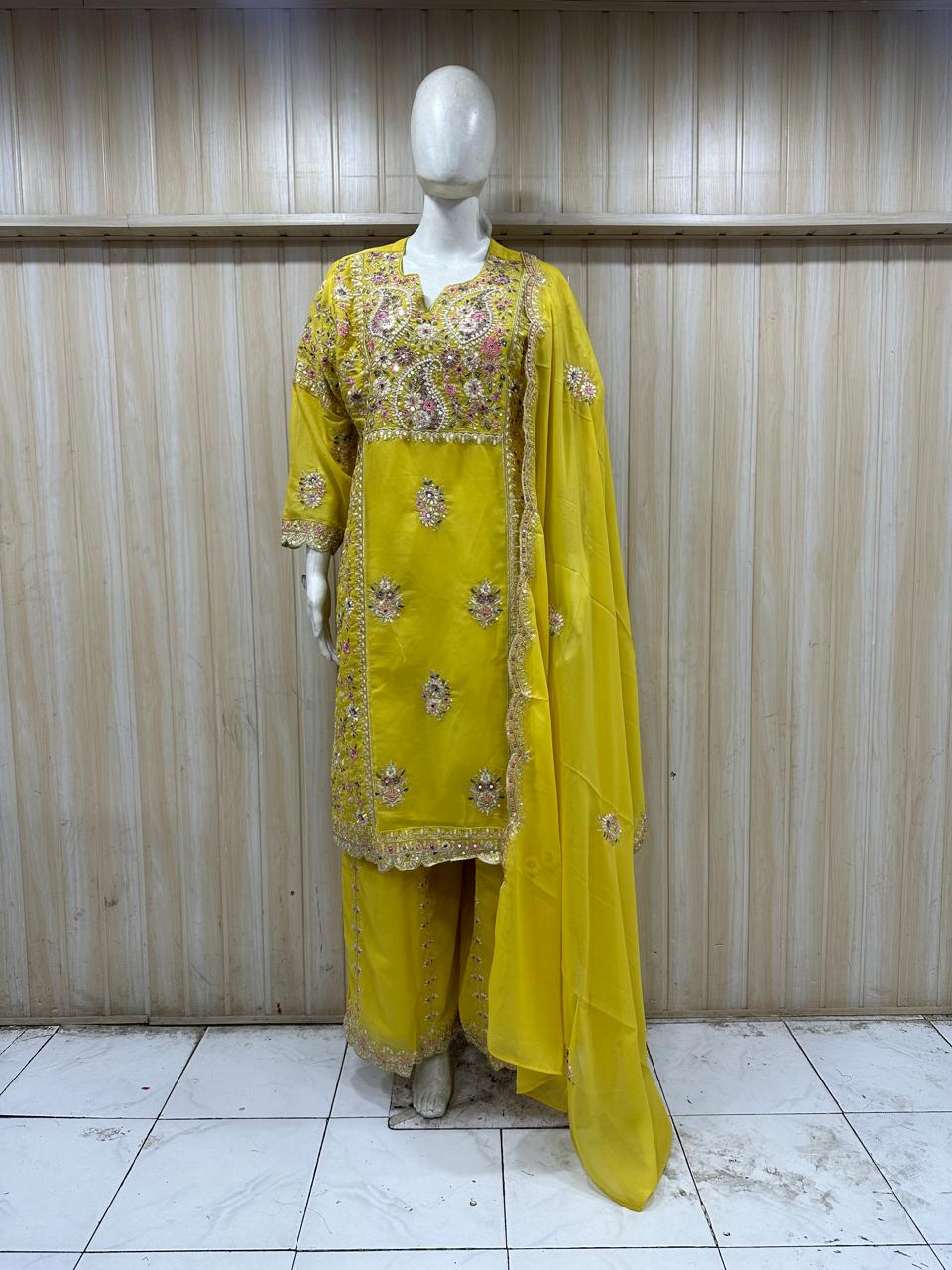 mannequin wearing a yellow embroidered outfit against a striped
