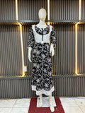 Mannequin wearing a black dress with white floral patterns against a textured