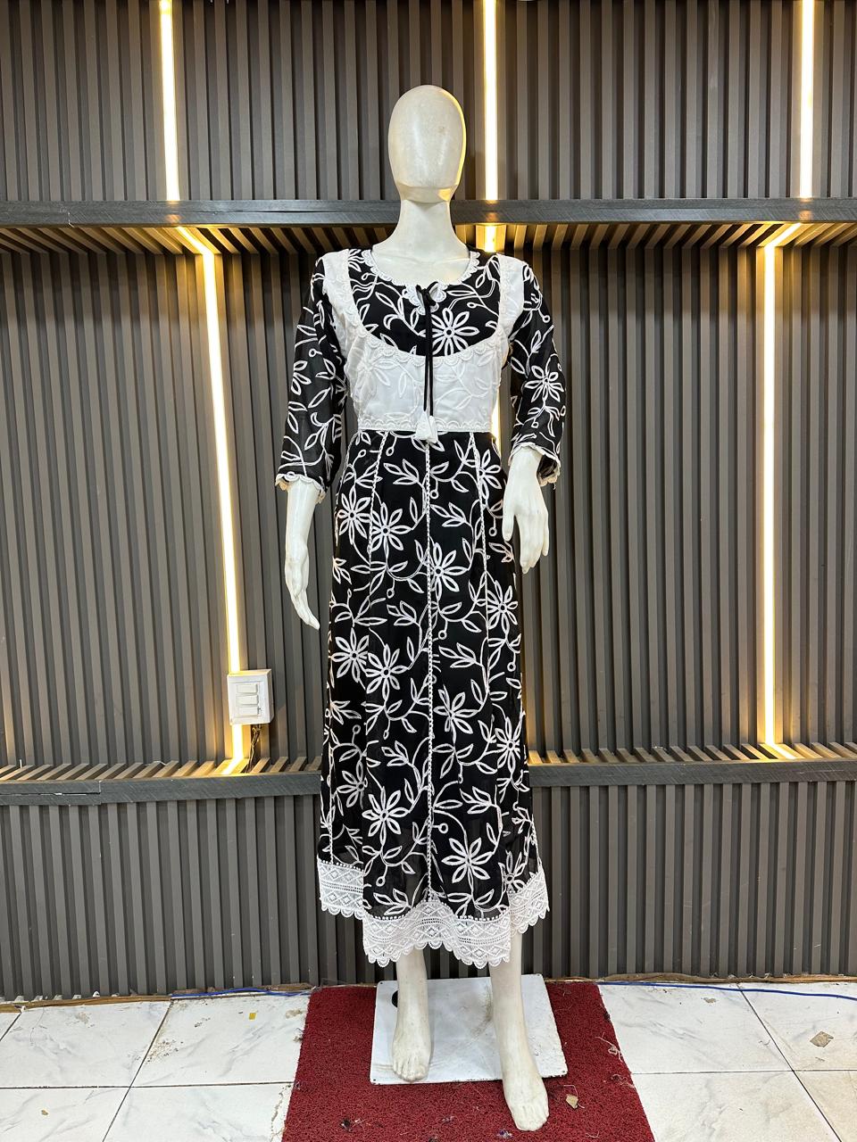 Mannequin wearing a black dress with white floral patterns against a textured