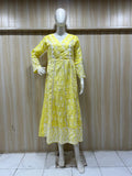 Yellow dress with floral patterns on a mannequin against a wooden panel background