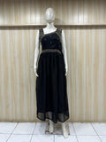 Black dress with intricate detailing on a mannequin against a wooden paneled