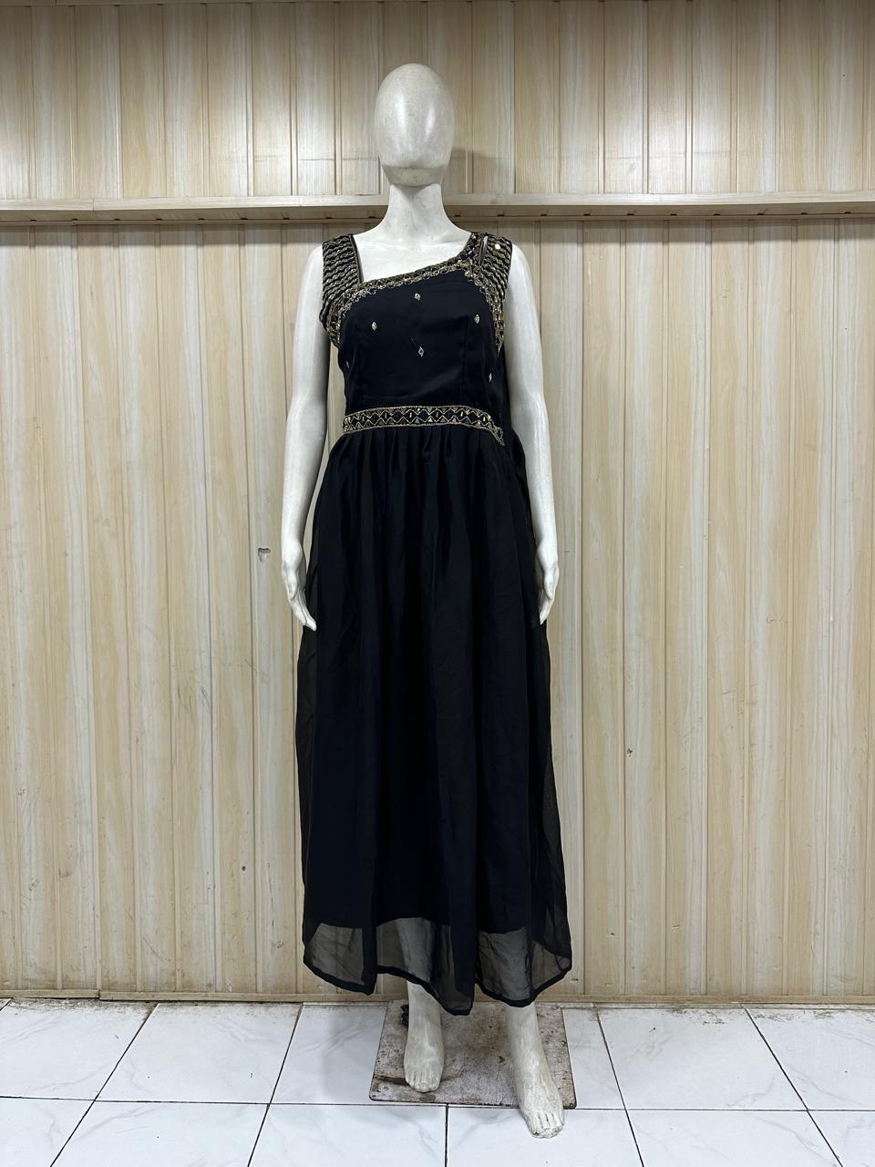 Black dress with intricate detailing on a mannequin against a wooden paneled