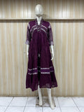 Mannequin wearing a purple dress with white embroidery against a wooden panel background