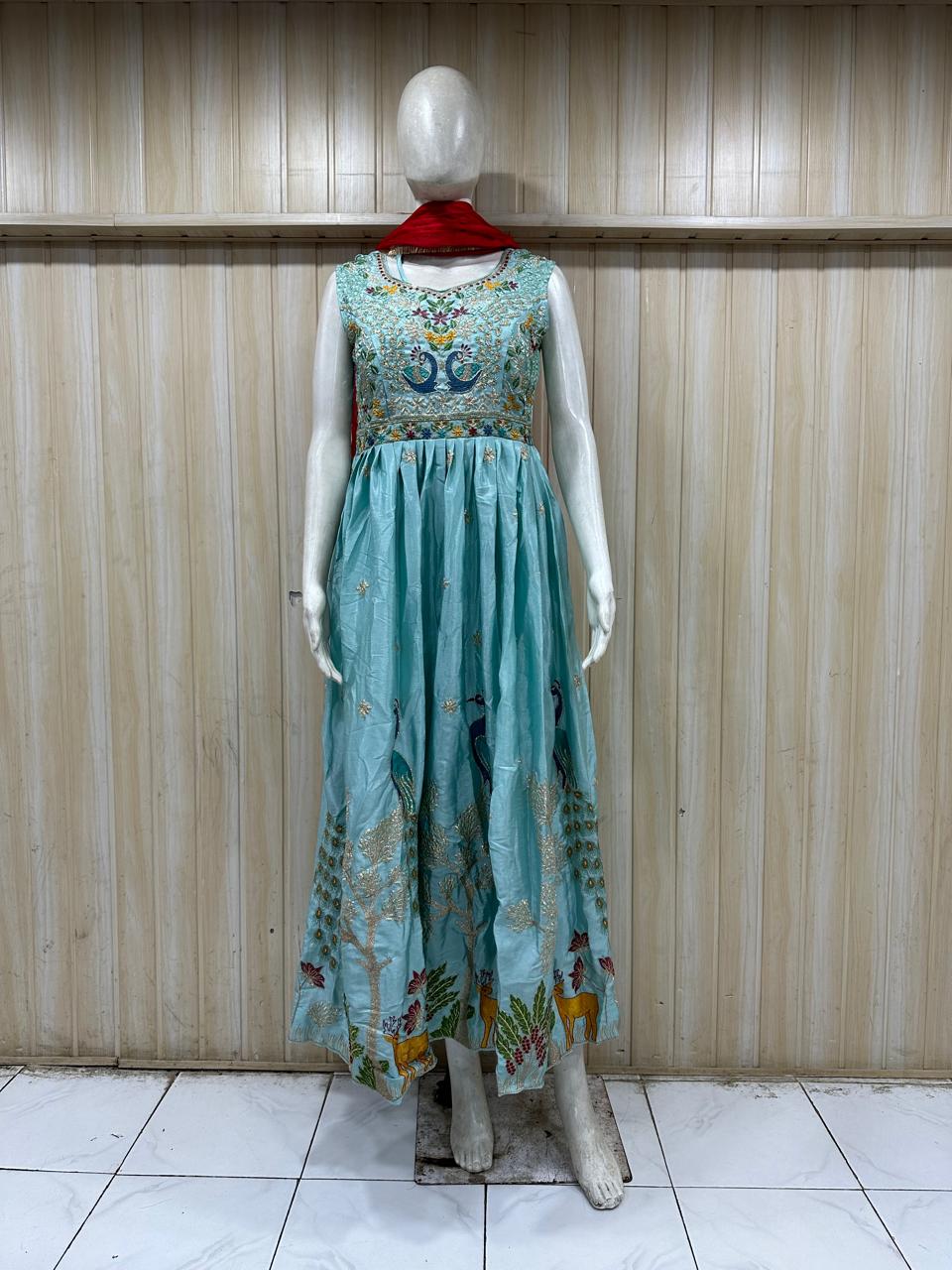 Mannequin wearing a long, light blue floral dress against a wooden panel background.