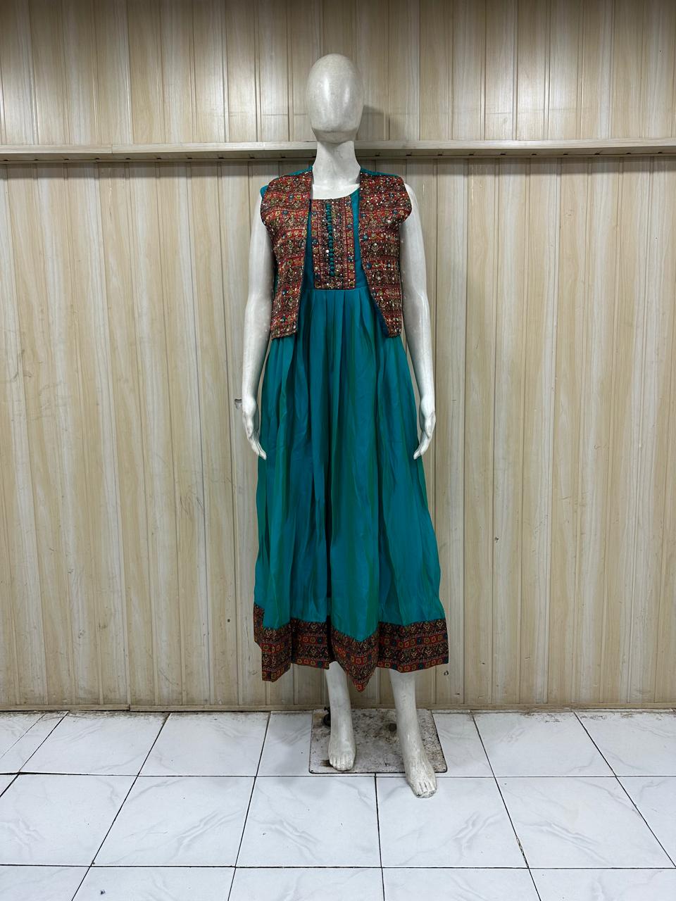 Mannequin wearing a teal dress with a patterned vest against a striped