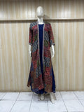 Mannequin wearing a long, patterned coat over a dark dress against a wooden panel background.
