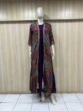 Mannequin wearing a long, patterned coat over a dark dress against a wooden panel background.