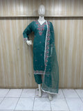 Green embroidered traditional outfit on a mannequin against a wooden panel background