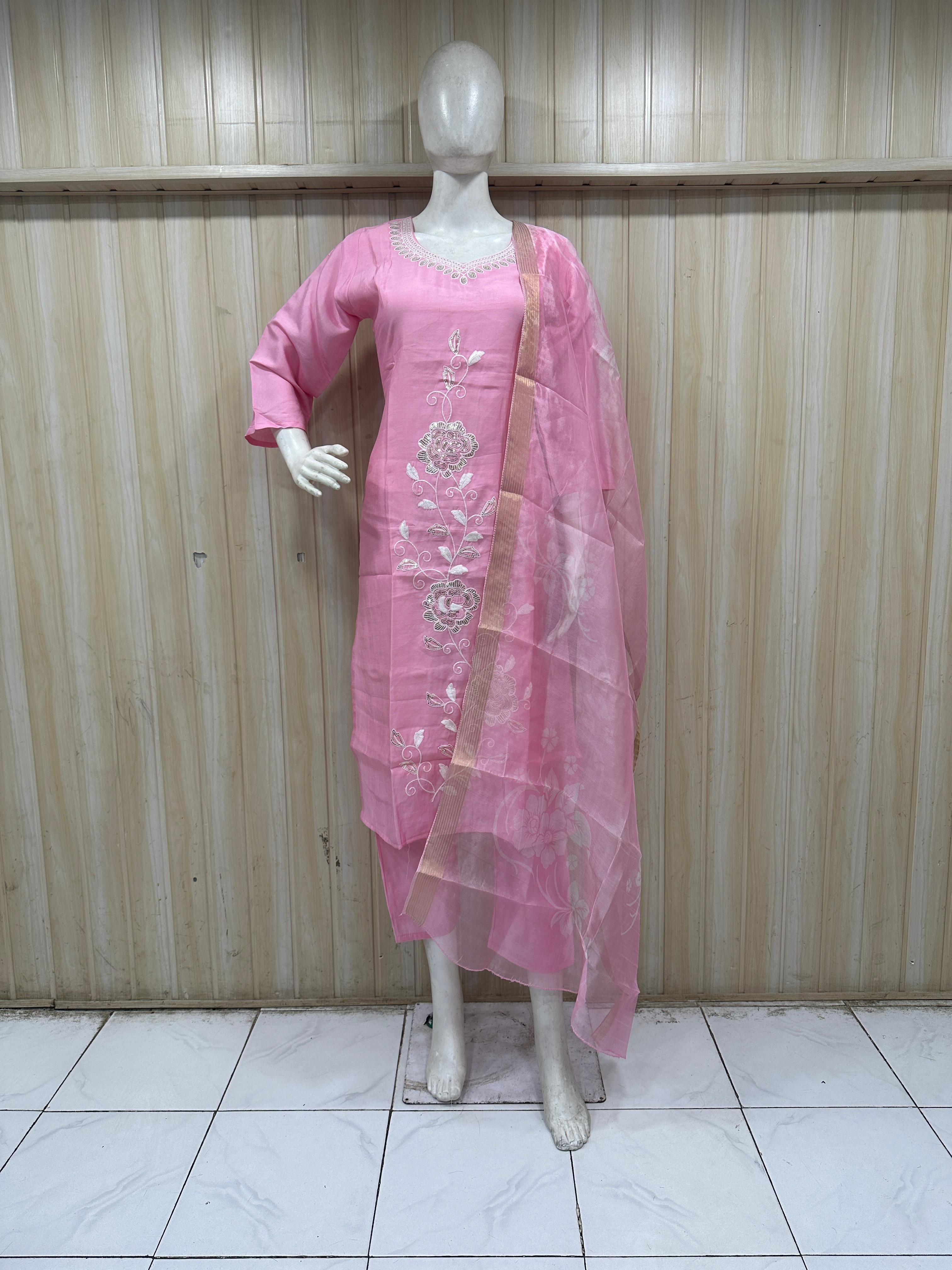 Mannequin wearing a pink traditional outfit with a sheer dupatta against a striped