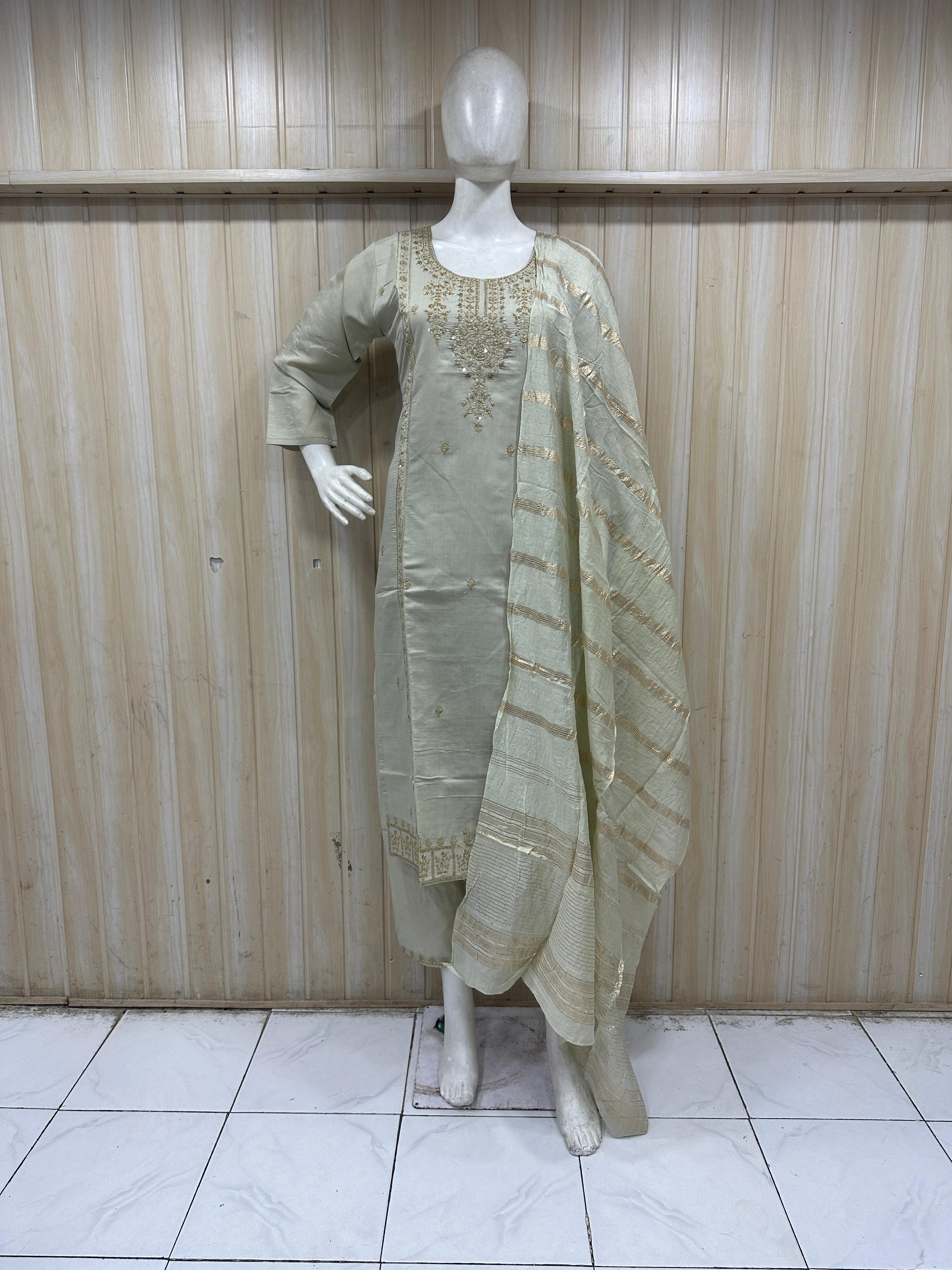 Mannequin wearing a light green traditional outfit with embroidery against a striped