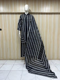 Mannequin wearing a black and white striped dress against a wooden panel background