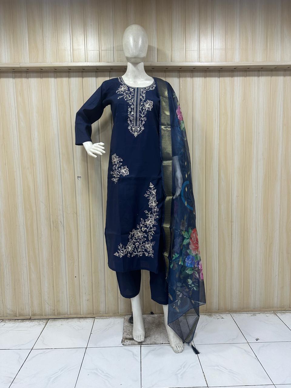 Navy blue embroidered outfit with a floral scarf on a mannequin against a striped