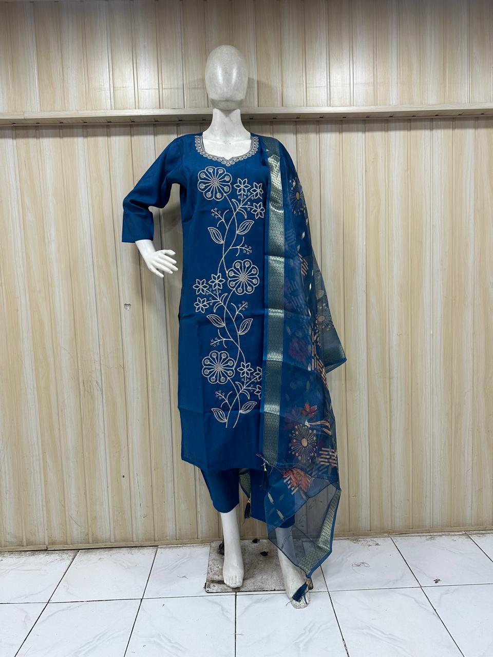 Blue embroidered outfit on a mannequin against a striped