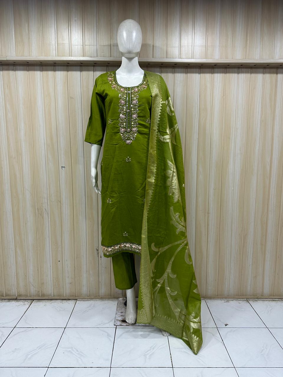 Green traditional outfit with embroidery on a mannequin against a striped
