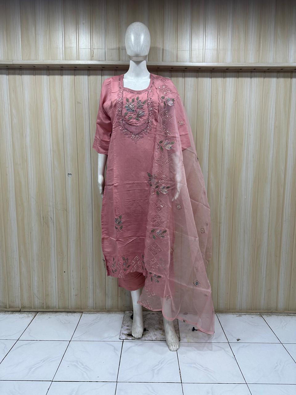 Mannequin wearing a pink embroidered dress against a striped